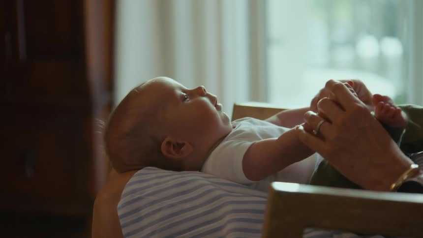 A tender moment between mother and child as she cradles her baby boy and gently plays with his hands