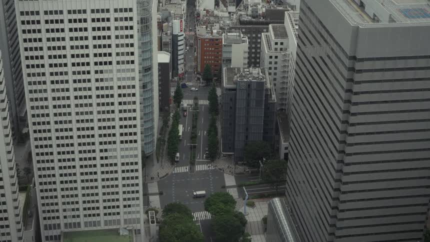 High-angle view of a city street with traffic moving between towering modern skyscrapers in Tokyo, Japan