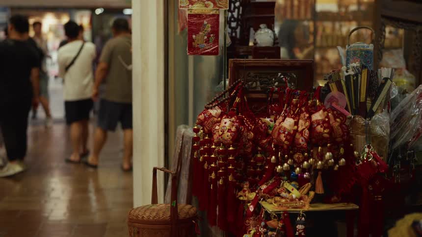 Red Chinese good luck tassels on display at a market stall with shoppers walking by in the blurred background