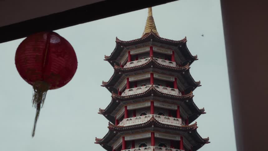 A static view of a traditional multi-story Chinese pagoda with a red paper lantern hanging in the foreground