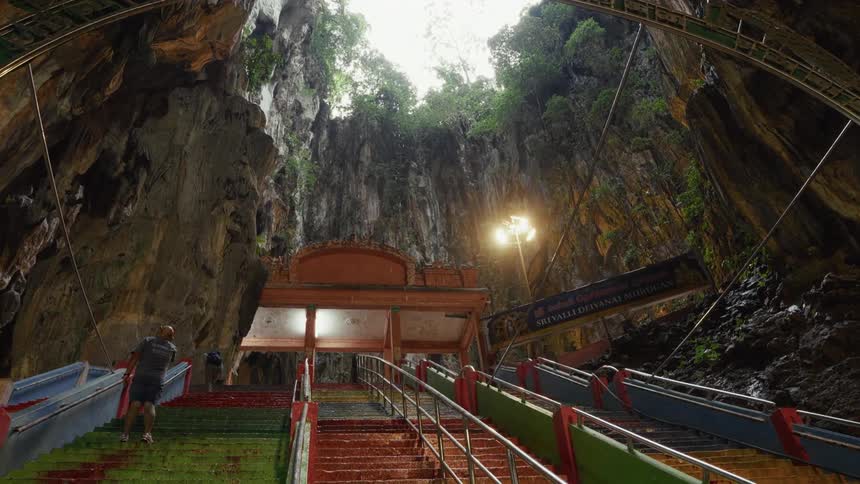 Looking up the colorful, wet stairs toward the sky opening inside the magnificent Batu Caves temple in Malaysia