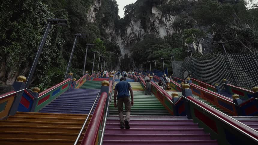 A man makes his ascent up the long, colorful rainbow staircase of the famous Batu Caves in Malaysia
