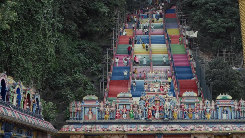 Tourists climb the vibrant, rainbow-colored steps of the Batu Caves temple in Malaysia