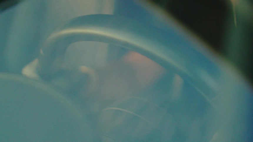 Dreamy close-up of a person's hands in classic white leather gloves gripping the steering wheel while driving a vintage car
