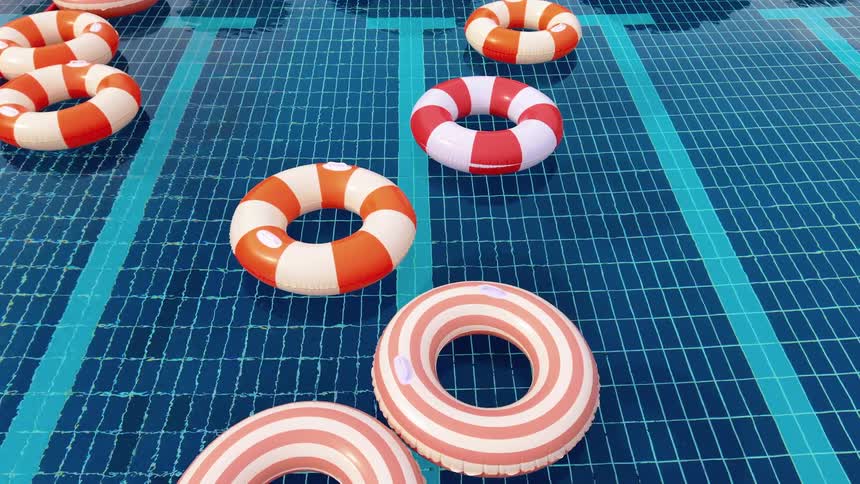 A variety of colorful striped inflatable rings gently float on the shimmering blue water of an empty swimming pool