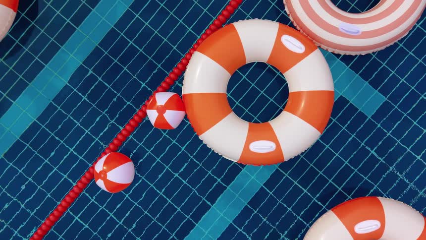 A top-down view of colorful inflatable rings and toys floating gently in a blue tiled swimming pool