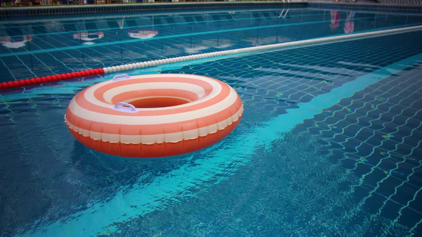 A red and white striped inflatable ring is tossed into a swimming pool and floats on the tranquil water