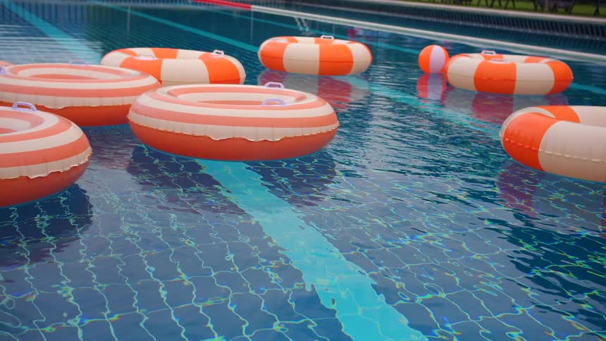 Colorful orange and white striped inflatable rings float peacefully in a bright blue swimming pool
