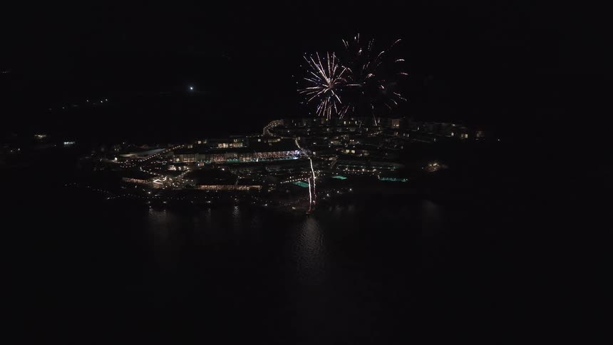 An amazing aerial view captures a dazzling fireworks display over a luxurious coastal resort at night