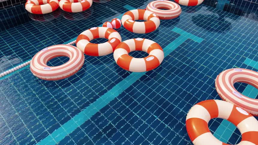 Red and white striped pool floats drift gently in a sparkling blue swimming pool on a sunny day