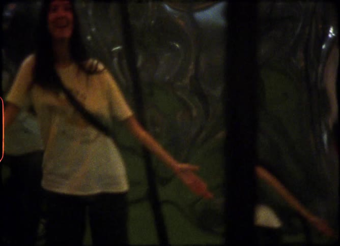 Vintage 8mm footage shows a woman and man looking at their warped reflections in a funhouse mirror