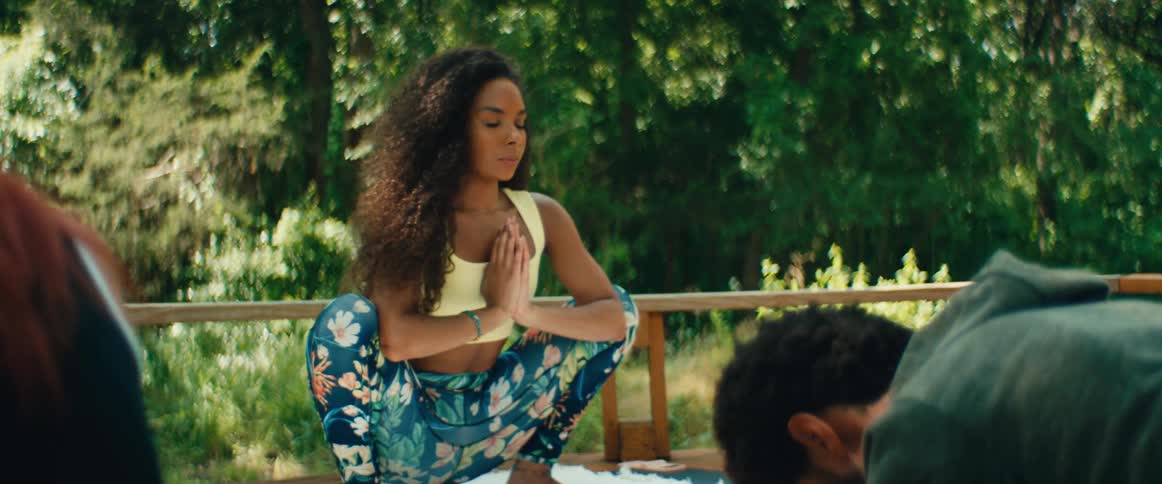 A serene female yoga instructor guides a class through meditative poses in a peaceful outdoor setting
