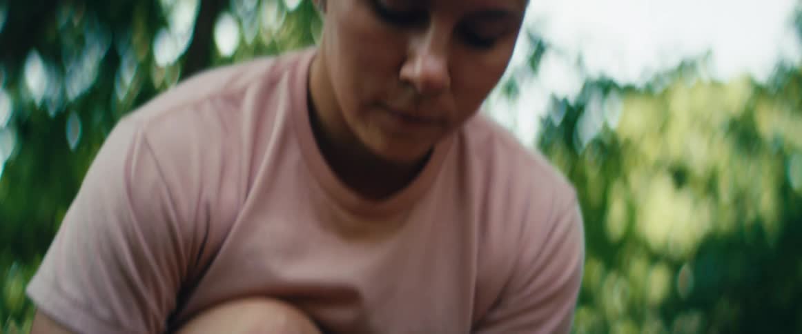 A female trail runner ties her bright orange sneakers in slow motion before standing up to begin her workout