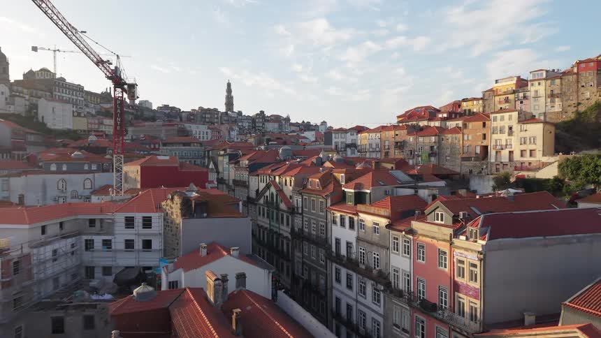 Scenic aerial view pulling back over the historic, red-tiled rooftops and colorful buildings of Porto, Portugal