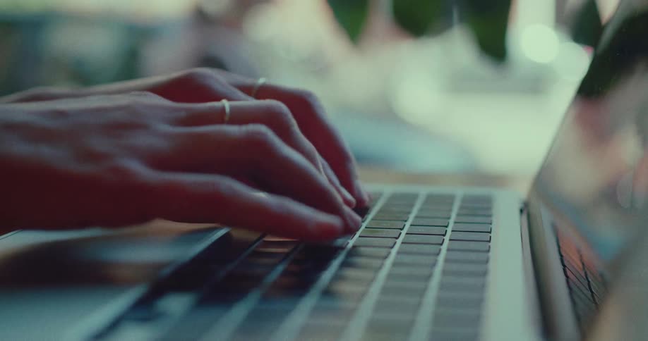 A close-up shot of a person's hands typing quickly on a modern laptop keyboard