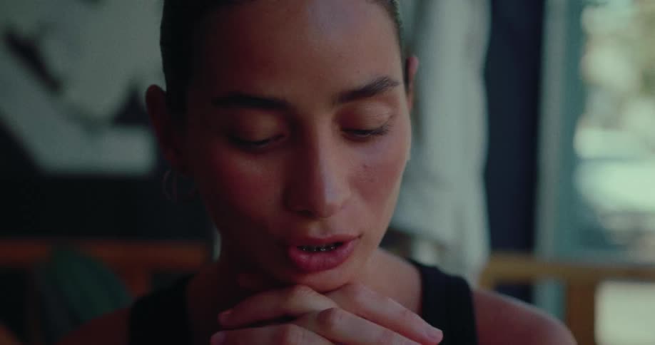 A close-up shot of a young woman engaged in an intimate and thoughtful conversation in a softly lit room