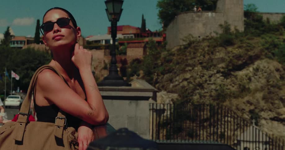 A stylish woman in sunglasses enjoys the warm sunshine while sightseeing in a historic European city