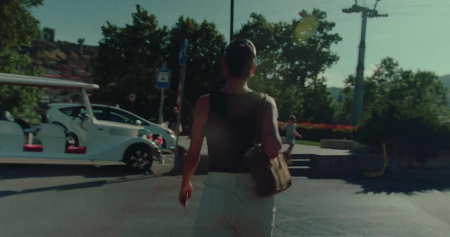 A stylish woman walks through a sun-drenched European city square on a beautiful summer day