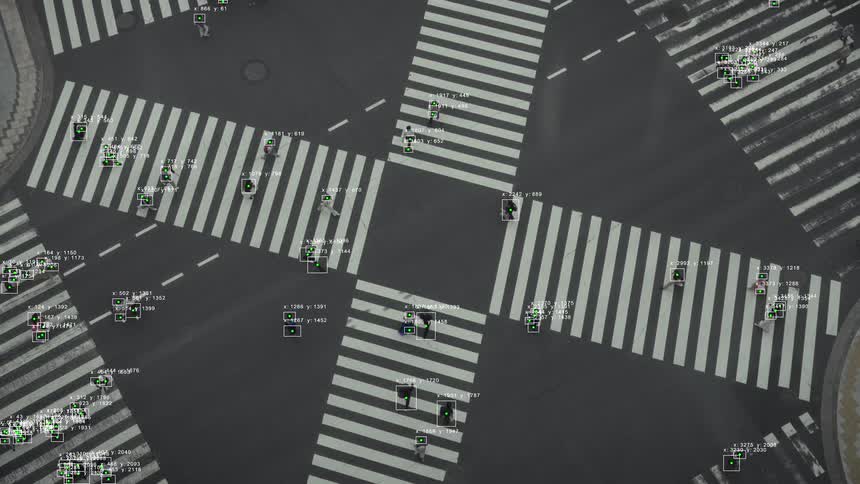 An overhead view shows artificial intelligence using object detection to track pedestrians crossing a busy city street