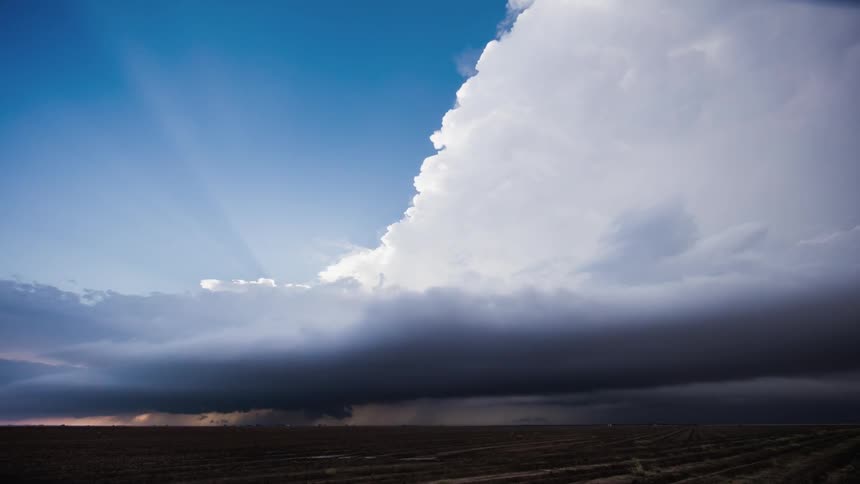 Clouds moving in the sky over a field and the sun is shining