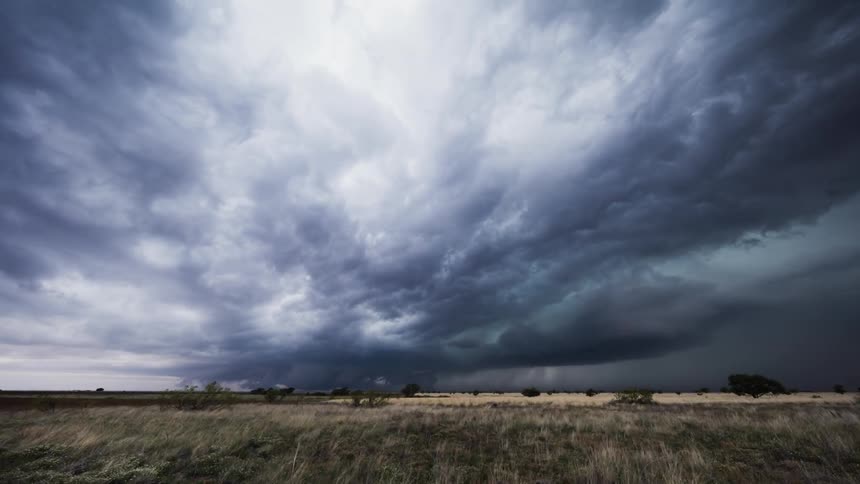 Storm clouds with lightning flashes form and move over a plain