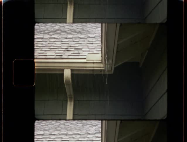 Rain falls from an overflowing house gutter in this vintage 8mm style film