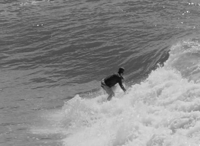 A surfer skillfully carves down the face of an ocean wave in this dramatic black and white slow motion shot