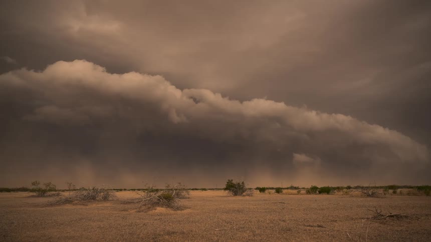 A time-lapse shows a massive dust storm, or haboob, rolling across the vast desert landscape under ominous, dark clouds