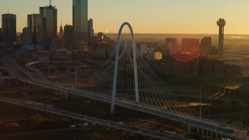 The iconic Margaret Hunt Hill Bridge stands before the downtown Dallas skyline during a beautiful sunrise