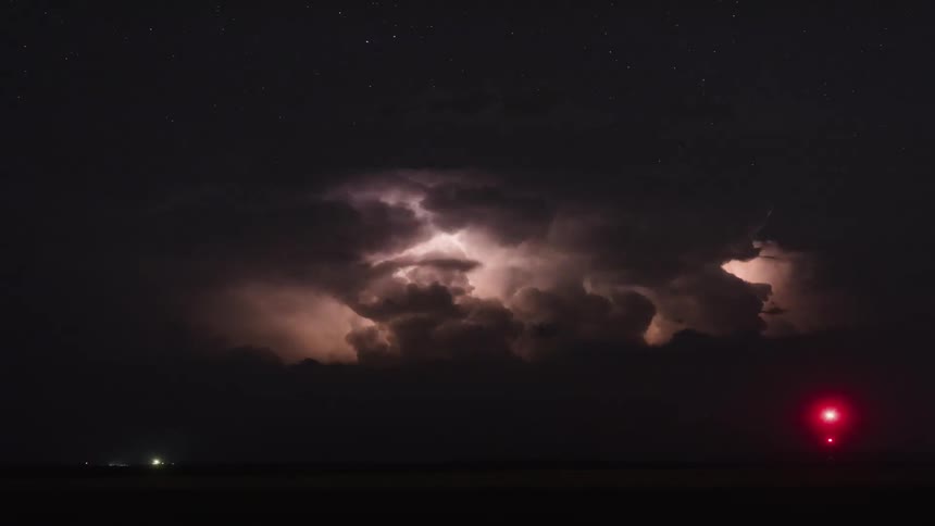 Lightning flashes through storm clouds at night