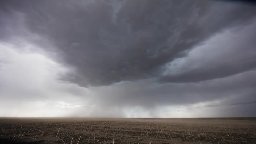 Storm clouds form and drop rain over a plain