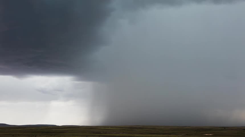 Storm clouds form and drop rain over a plain