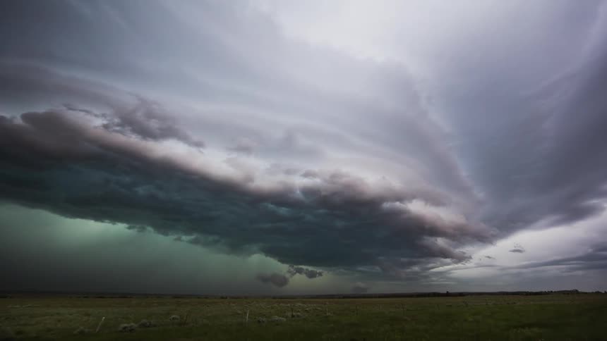 Storm clouds float over an open field as lightning flashes