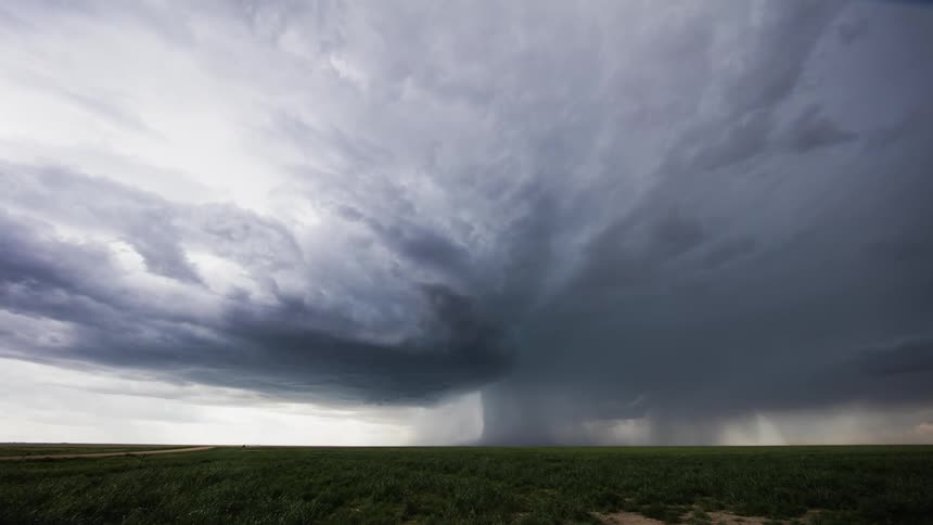 Storm clouds form and drop rain over a plain