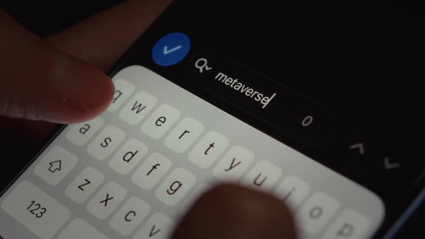 A close-up shot of fingers typing the word 'metaverse' into a search bar on a smartphone screen