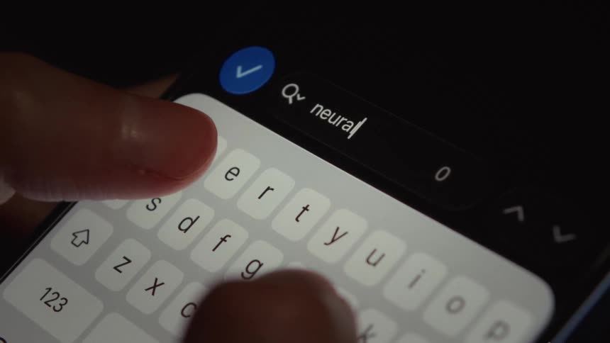 A close-up shot of a person's finger typing the word 'neural' into a smartphone search bar