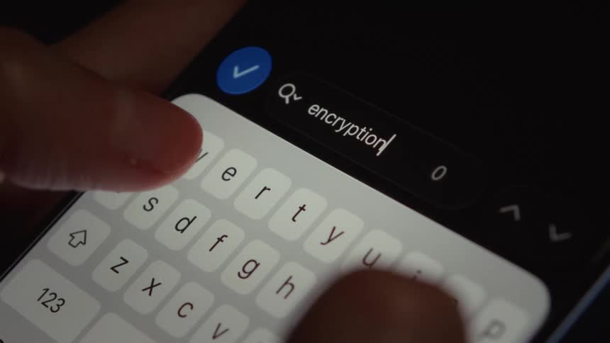 A close-up of fingers typing the word 'encryption' into a search bar on a smartphone screen