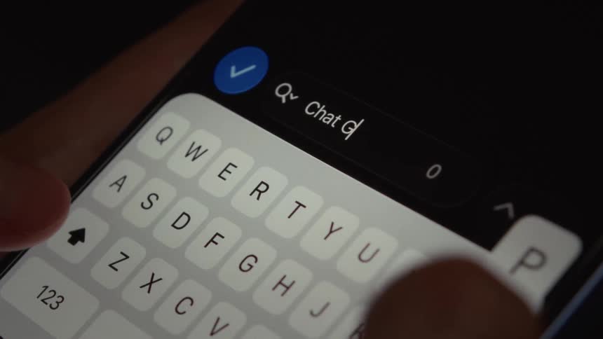 Close-up of a person's hands searching for 'Chat GPT' on a smartphone in dark mode