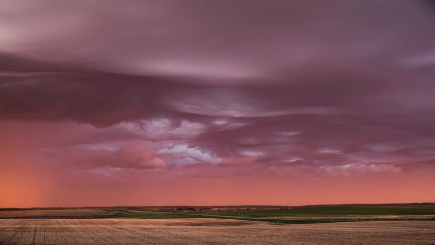 Storm clouds move across the field as rain pours down