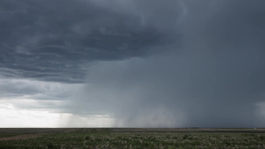 Storm clouds form and drop rain over a plain