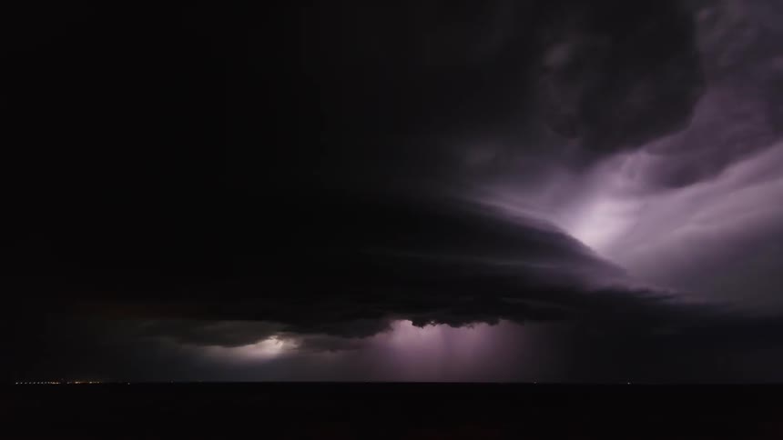 Storm clouds and lighting move over a plain in the dark