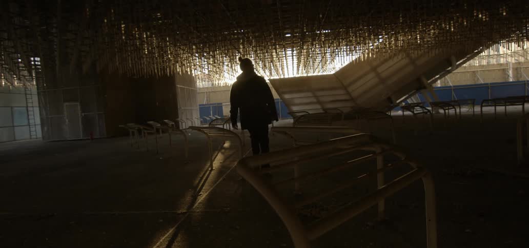 A man is walking through a building with barriers at dusk