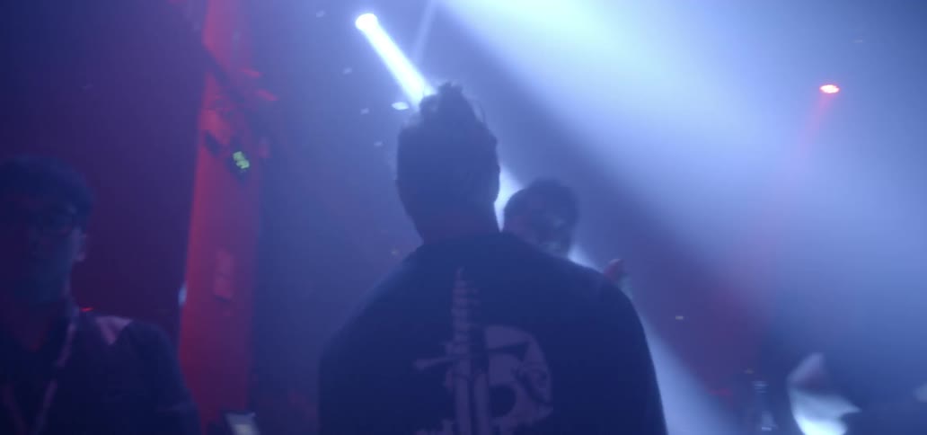 Man walking through crowd of people in club with flashing lights