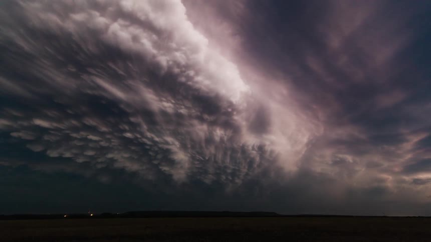 Heavy storm clouds flicker with lightning flashes