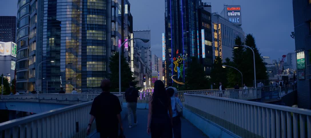 Slow motion following shot of people walking on a bridge through the vibrant, neon-lit streets of Shinjuku, Tokyo at dusk