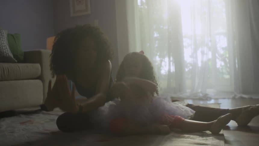 A mother and child practice dance moves in a living room
