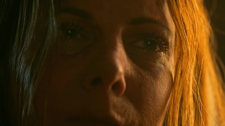 An intense and emotional close-up of a sorrowful woman's tear-filled eyes under dramatic, warm lighting