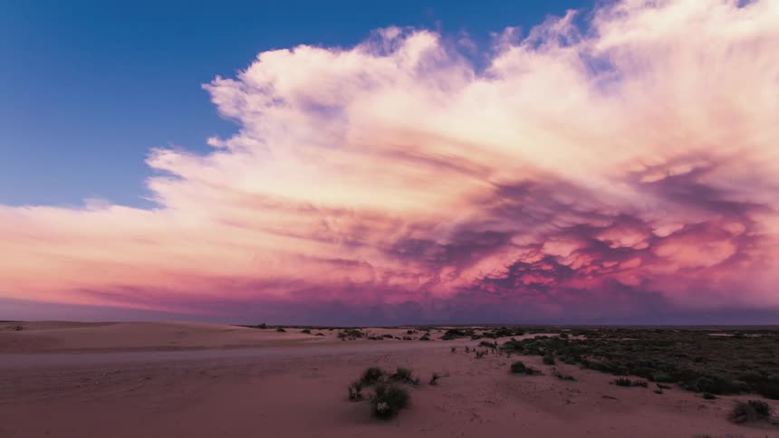 Clouds move across a desert landscape at dawn