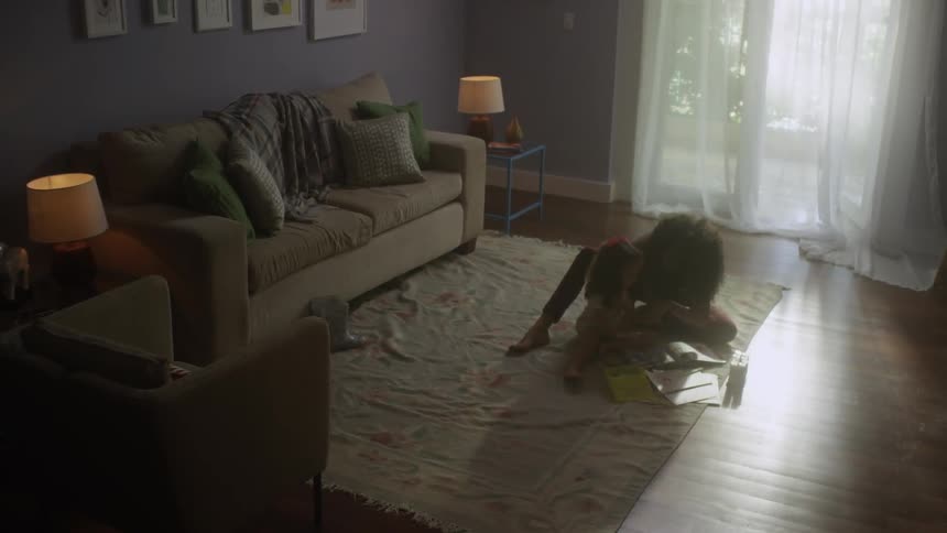 Woman and child drawing or coloring while sitting on a living room floor