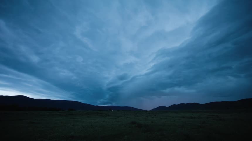 Clouds and lightning move over a roadway and plain